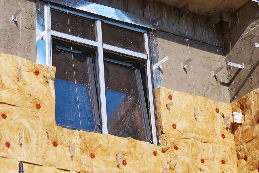 Plastic double glazing in a new house. Insulation of the facade of a house under construction using modern technologies using mineral wool. Preparing for a cold winter in an energy crisis.